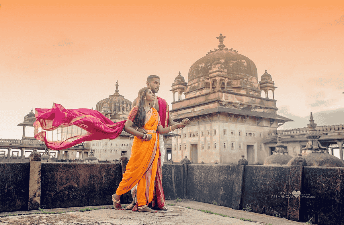 Pre-wedding photoshoot of a couple posing in front of the Jahangir Mahal, wearing beautiful traditional attires.