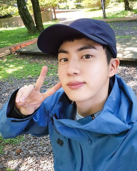 A picture of  RUN JIN on blue jacket with a face cap 