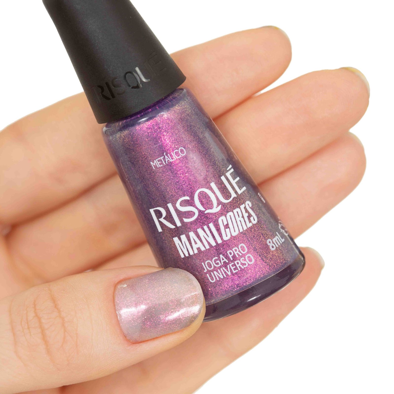 Uma mulher segura o esmalte Joga pro Universo com as unhas pintadas de roxo metálico.