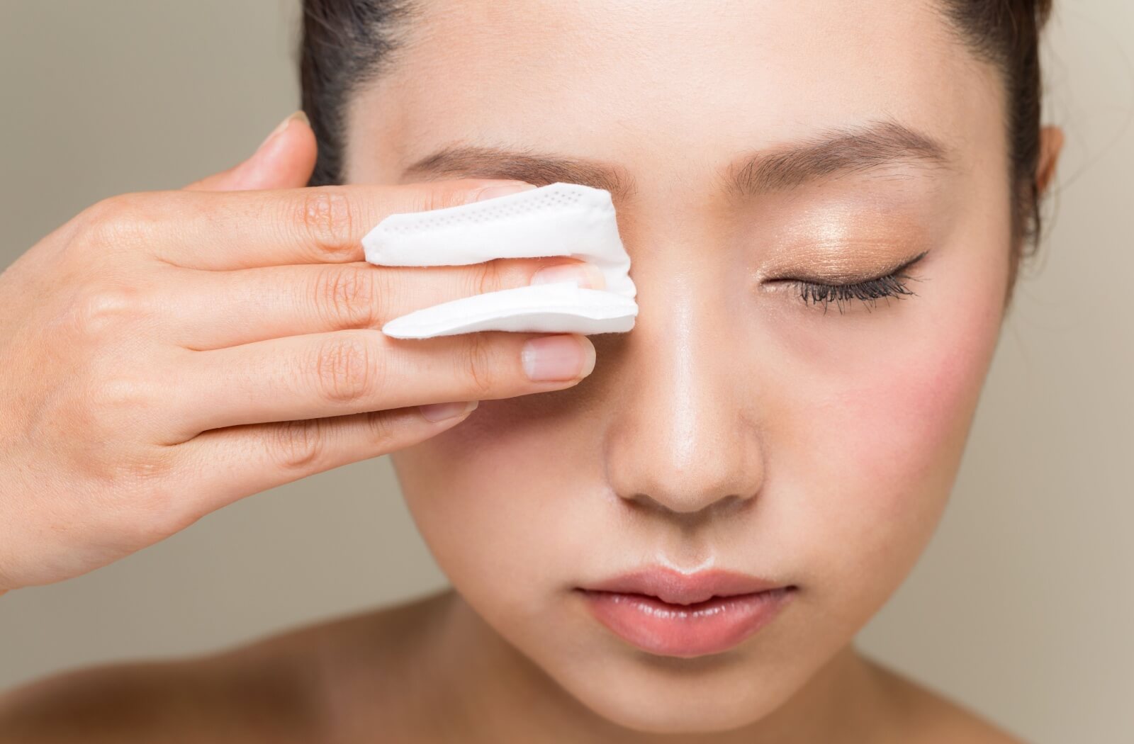 A woman removing her eye makeup with products that are drying out the skin under her eyes