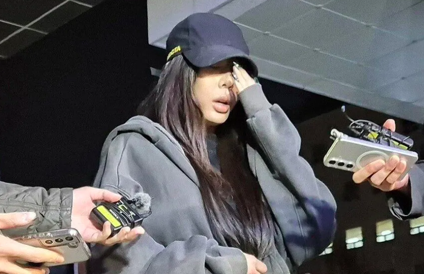 This contains an image of Jessi dressed casually in a zip-up hoodie and black cap