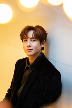 This  contain an image of  2PM's Nichkhun leaning against a wall with lights in the background