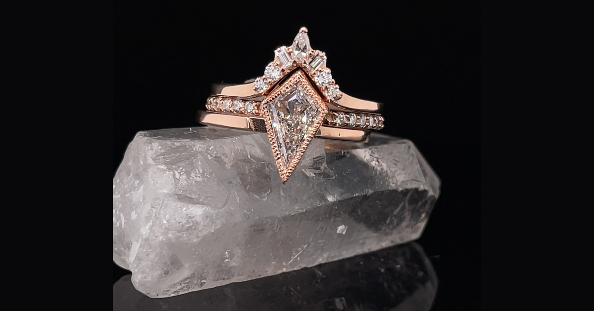 Beautiful kite shaped diamond engagement ring in rose gold with a black background.