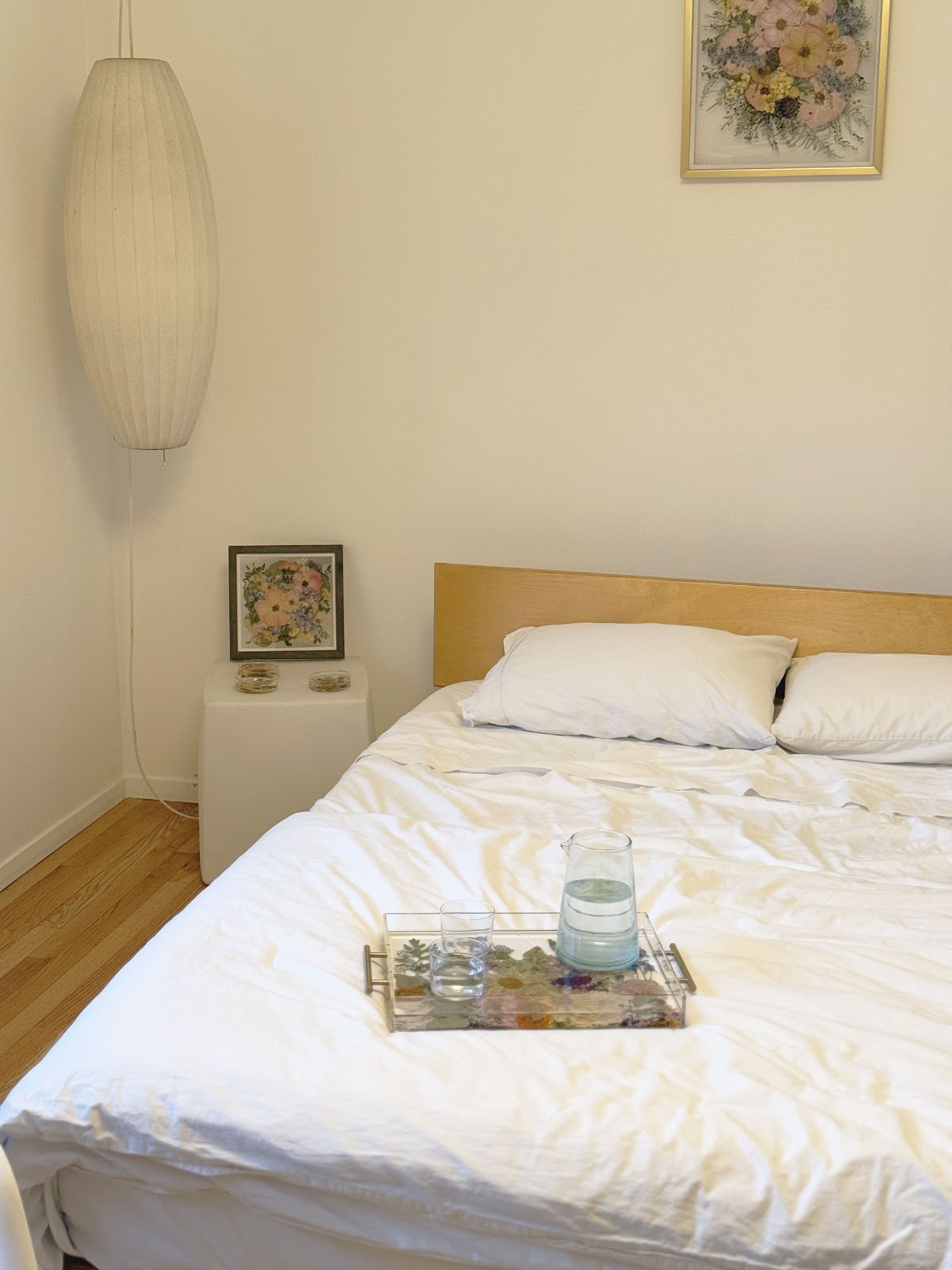 a bedroom with frame and resin preservation pieces on the bedside table and a frame on the wall