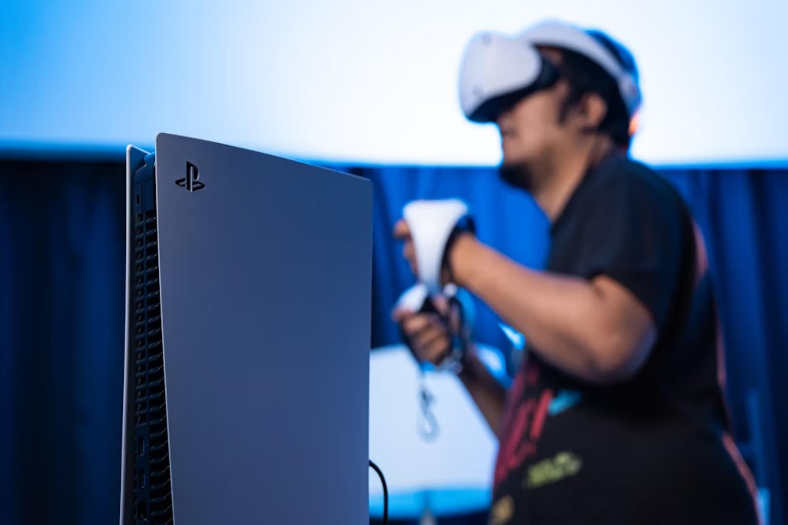 man in black shirt wearing VR headset behind computer