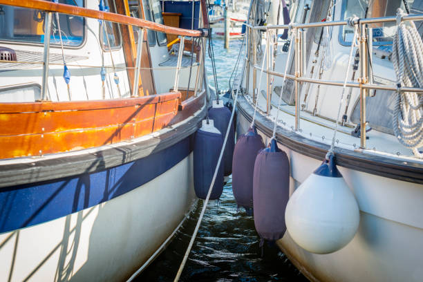 Two boats docked side by side with fenders