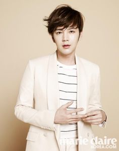 This contain an image of Jang Geun Suk putting on a milk color suit an a white inner shirt  