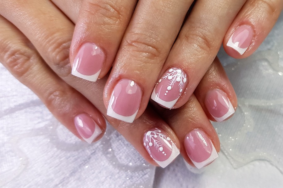 Floral accents soften French nail tip design with delicate petal details.