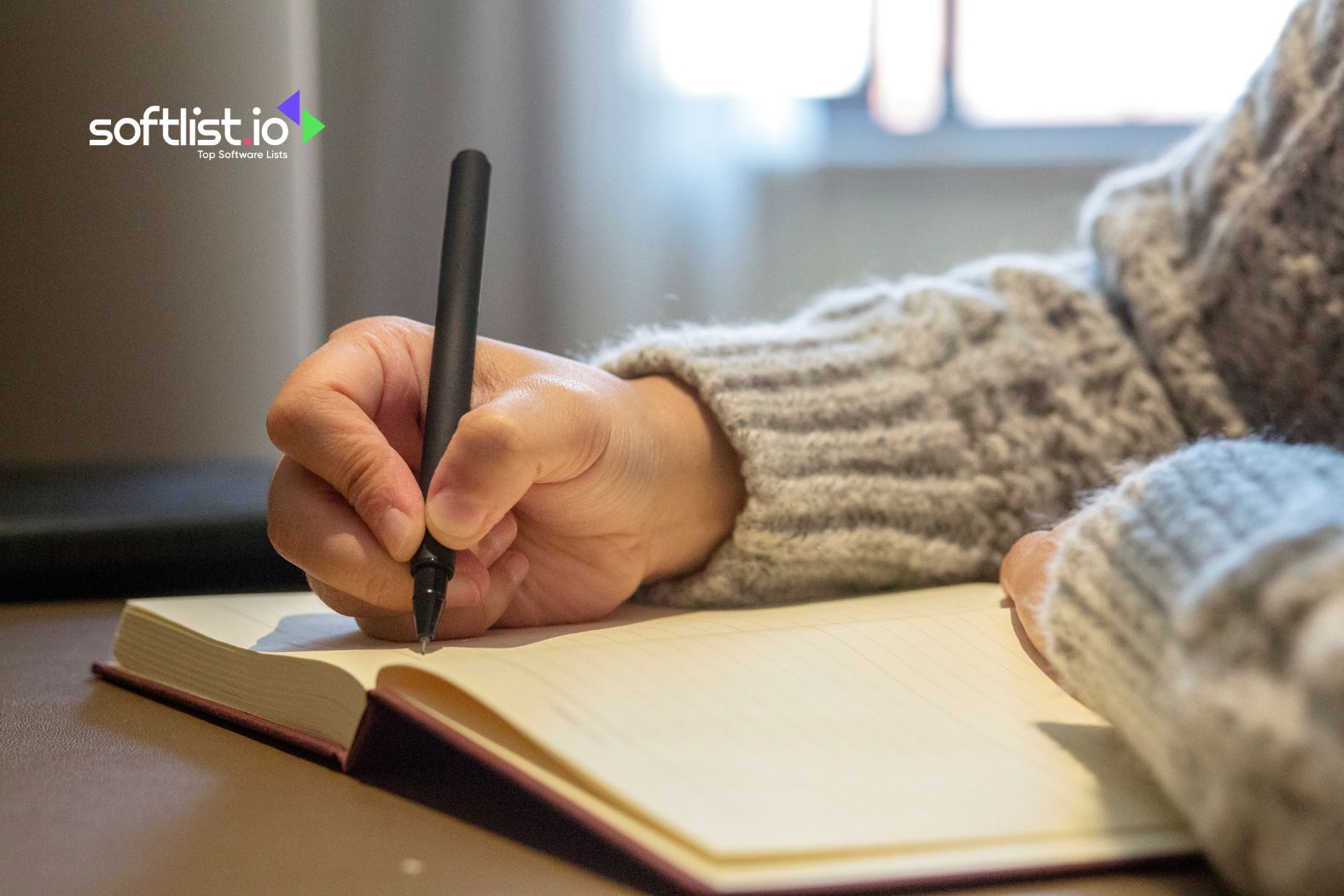 Handwriting in a notebook with a black pen, cozy sweater visible