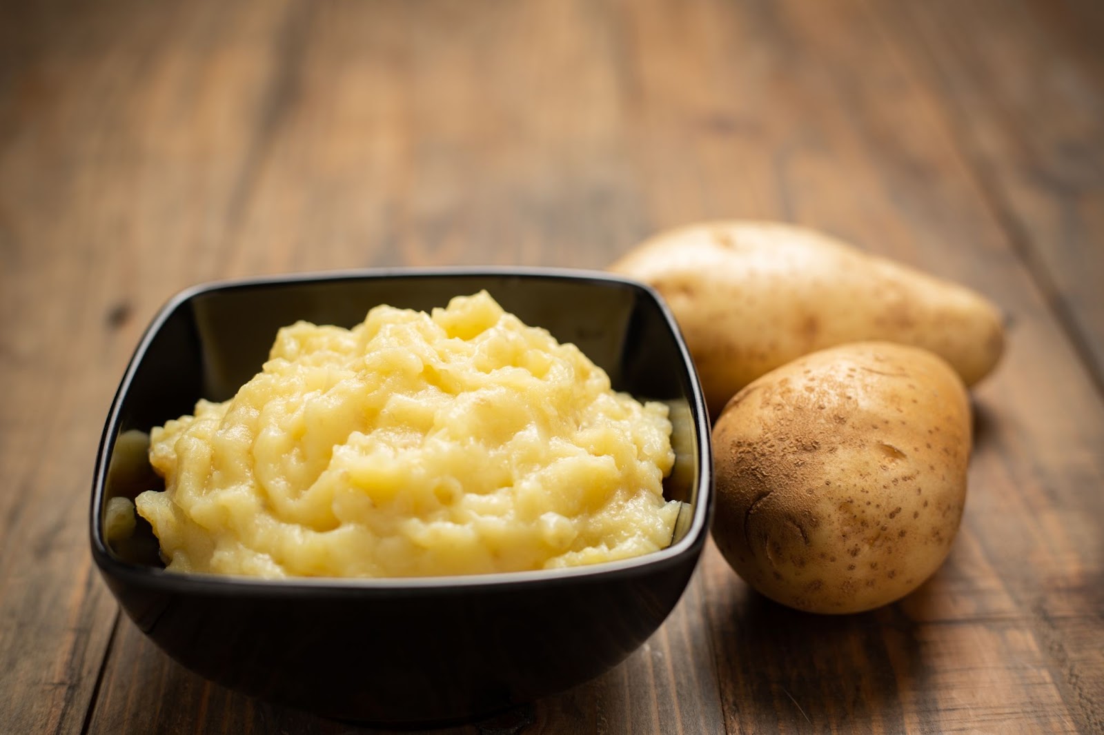 Bowl of mashed potatoes on a wooden table