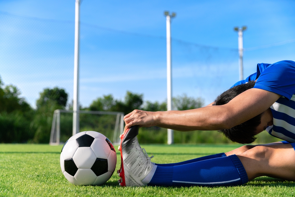 A soccer player doing static stretches before a game.