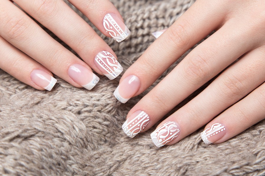 Lace patterns add vintage charm to a sophisticated French nail tip design.