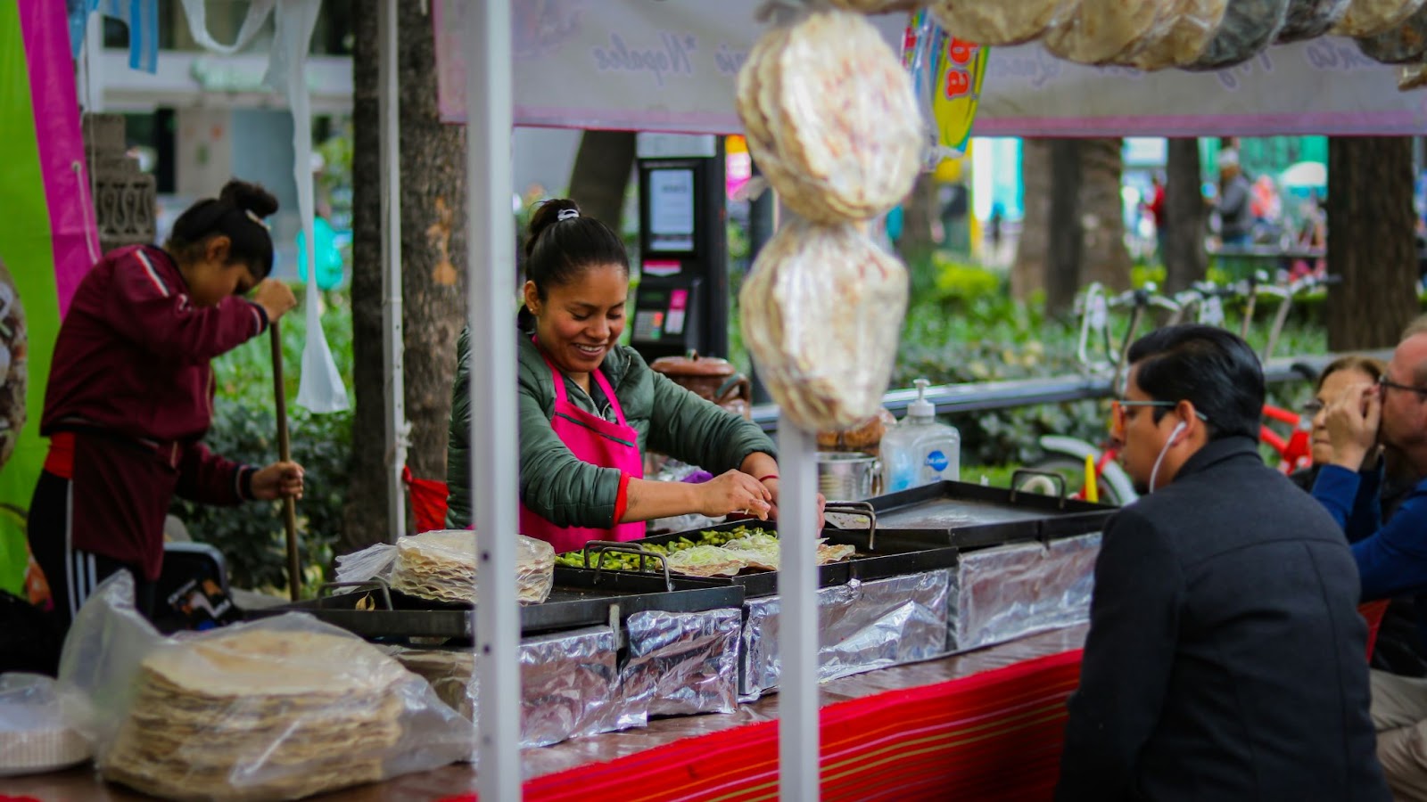 Vendedora de comida preparando tortillas en un puesto de comida al aire libre