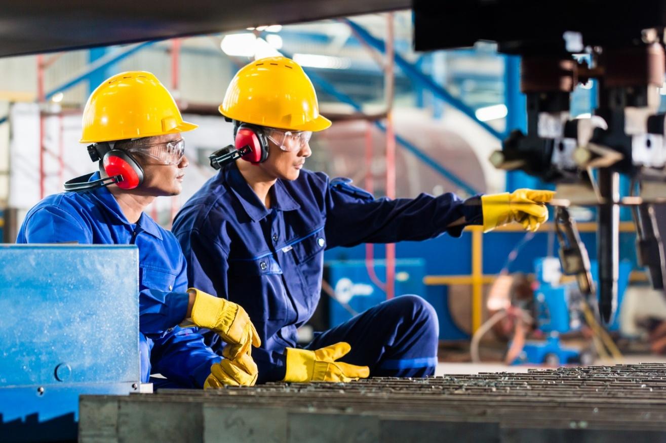 A group of people wearing hard hats and gloves pointing at something

Description automatically generated