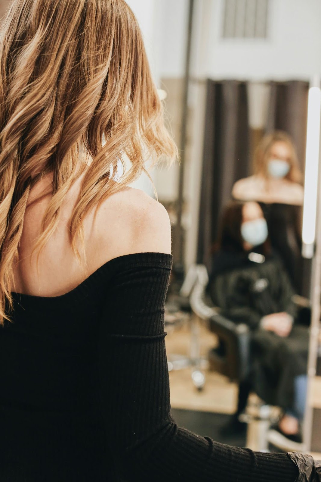 Woman viewing her styled hair in salon mirror after extension installation