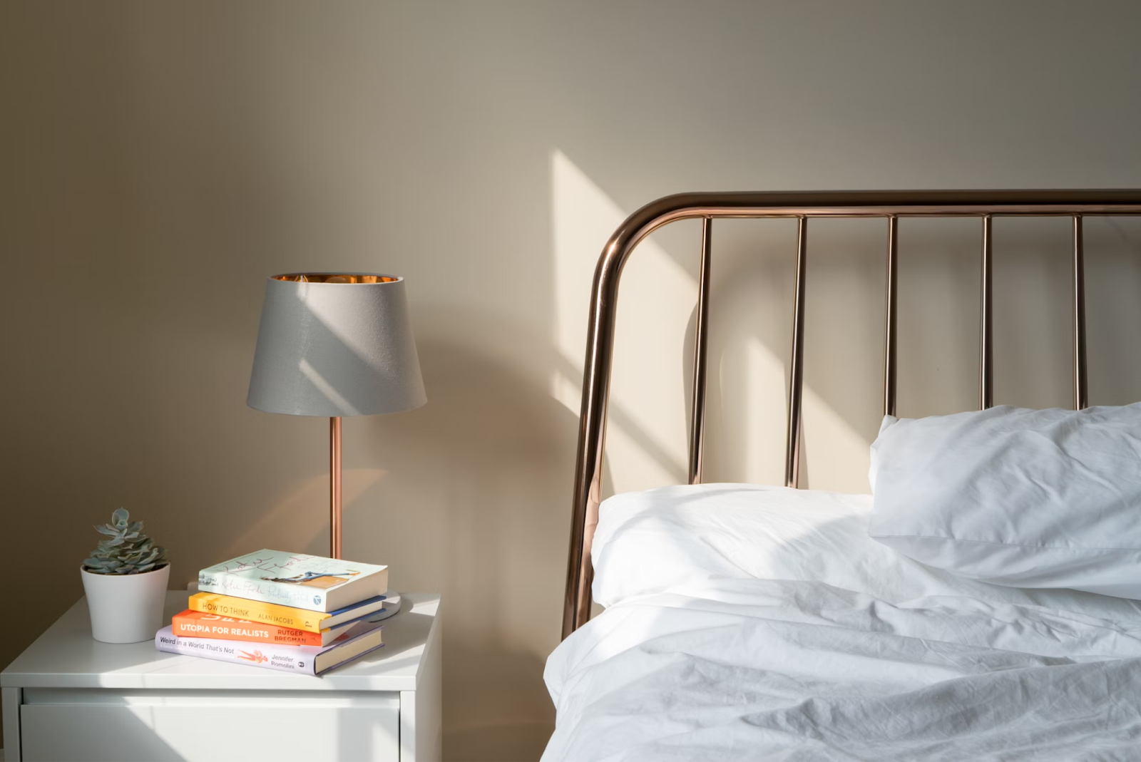 Bed with white sheets and table with books on