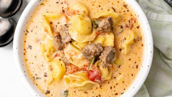 Easy Crockpot Sausage & Tortellini Soup in a white bowl.