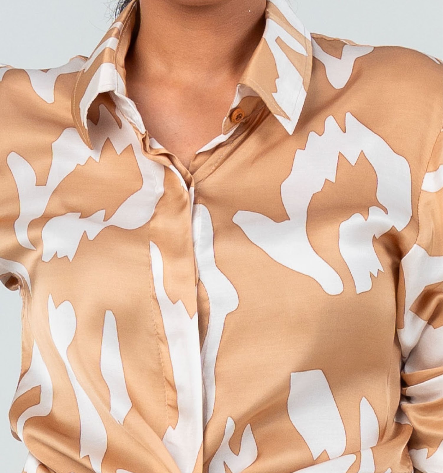 A closeup image showing long sleeved women's batik shirt in tan rimba from batik boutique, standing in a office