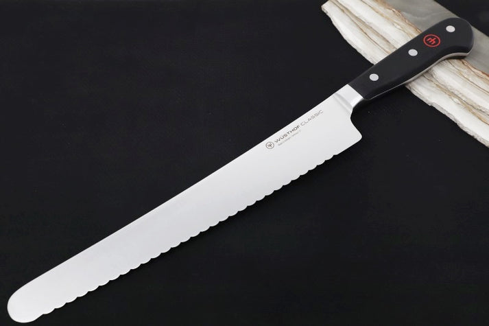 An image showing the Wusthof Classic Super Slicer, identifiable by its long, serrated blade and the triple-riveted handle typical of Wusthof's Classic line.