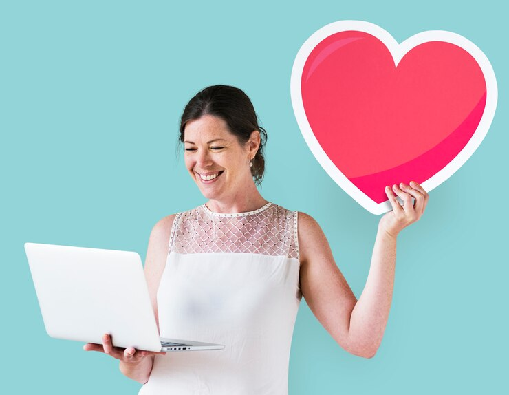 Woman smiling while holding a laptop and a heart emoticon
