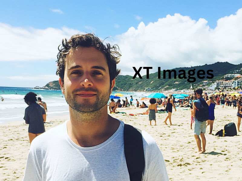 A watermarked picture of a man at the beach with tourists in the background