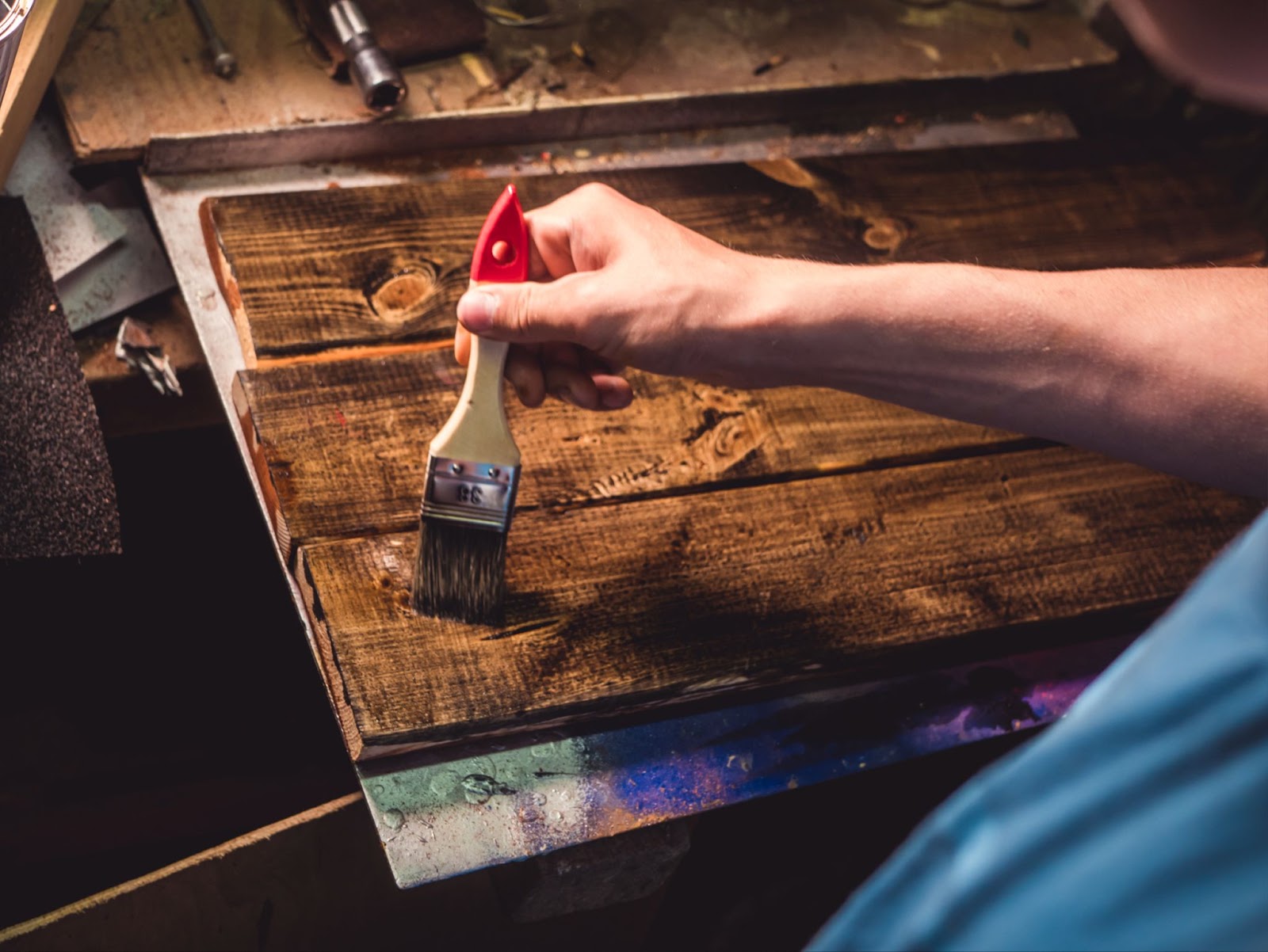 A closeup shot of a carpenter's hand staining wood planks.