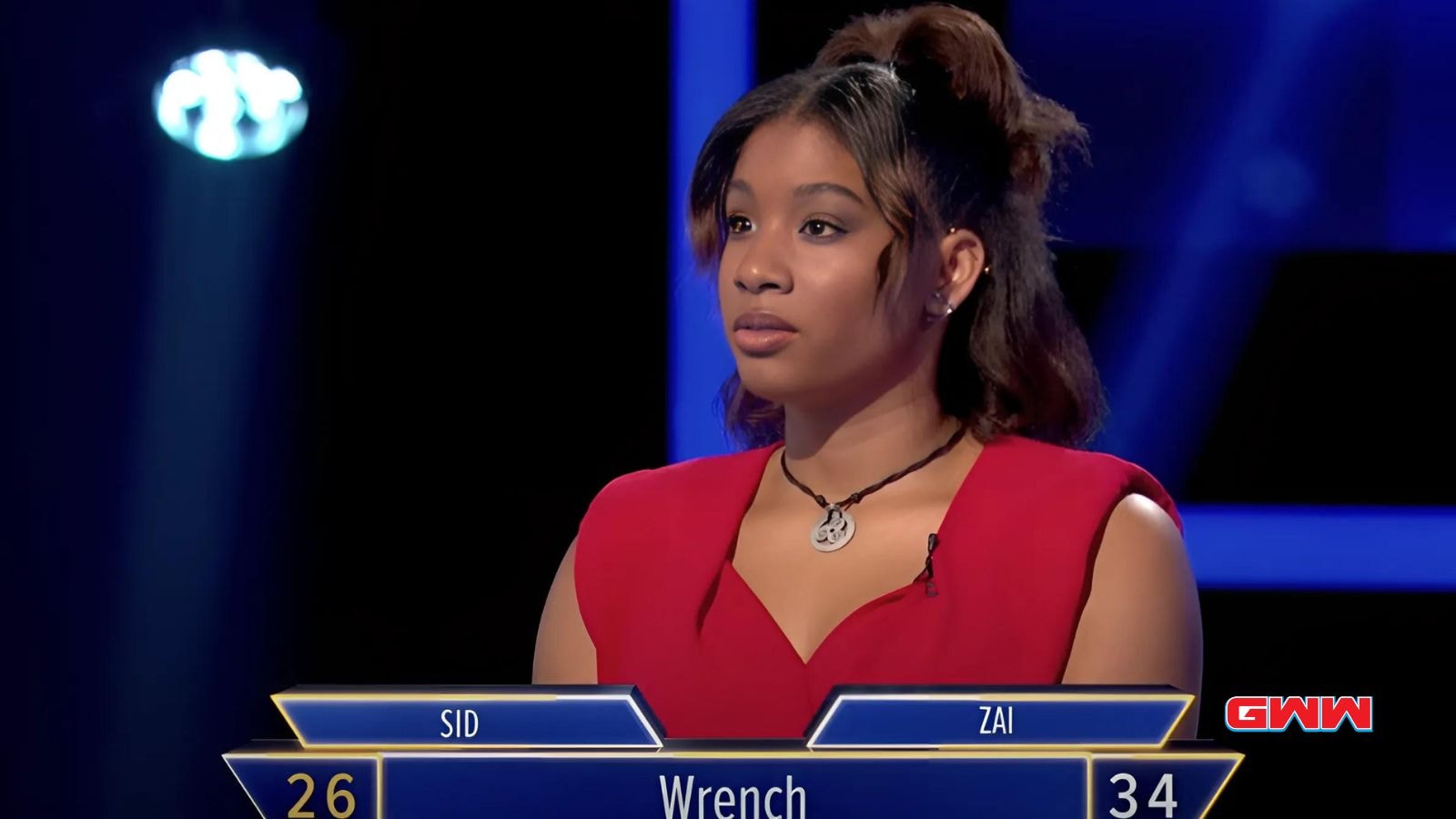 Young woman in red dress, focused during a game show question.