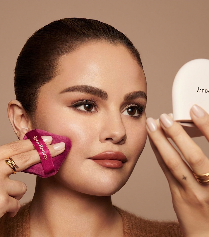 A person applying makeup with a small pink sponge

Description automatically generated