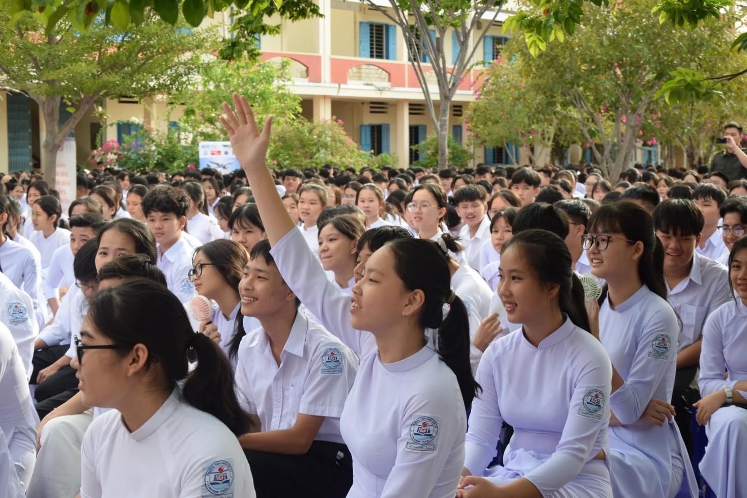 A group of people in white shirts raising their handDescription automatically generated