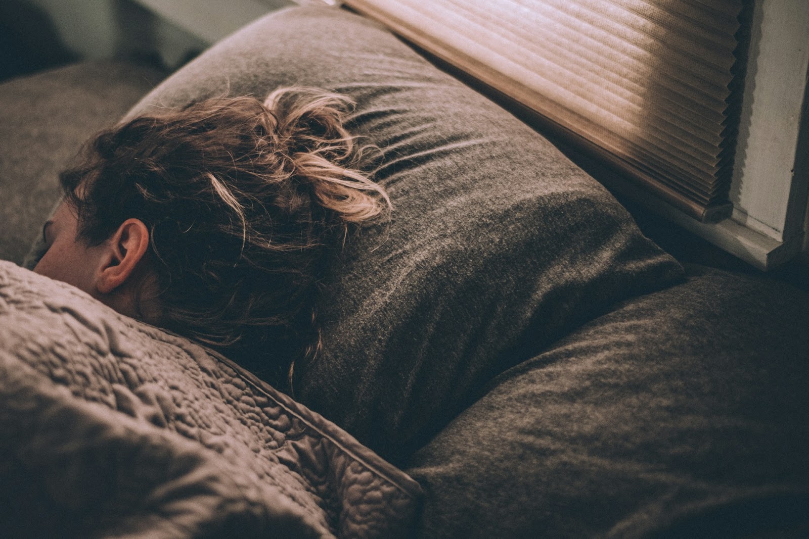 A woman wrapped up in bed, sleeping under duvets