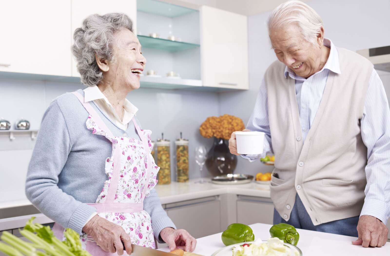 A happy senior couple prepares a healthy snack in their indpendent living home kitchenette.