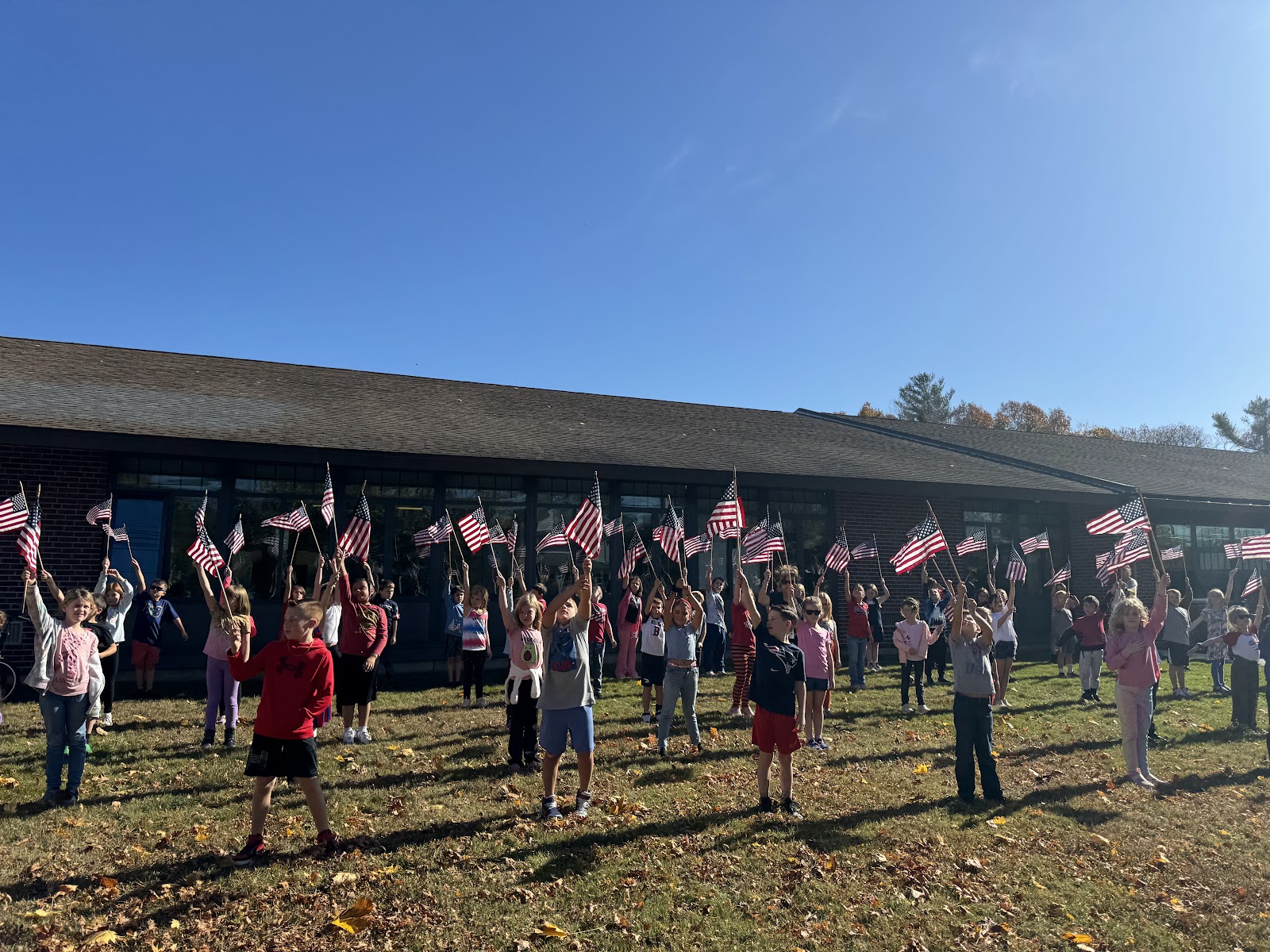 image of students holding flags on the front lawn of the school