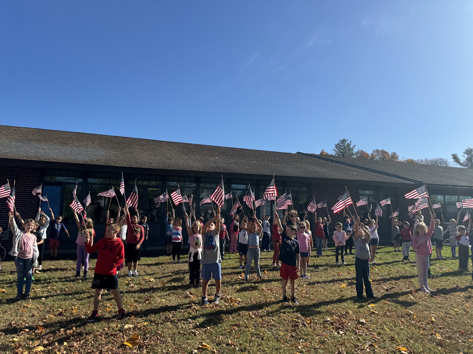 image of students holding flags on the front lawn of the school