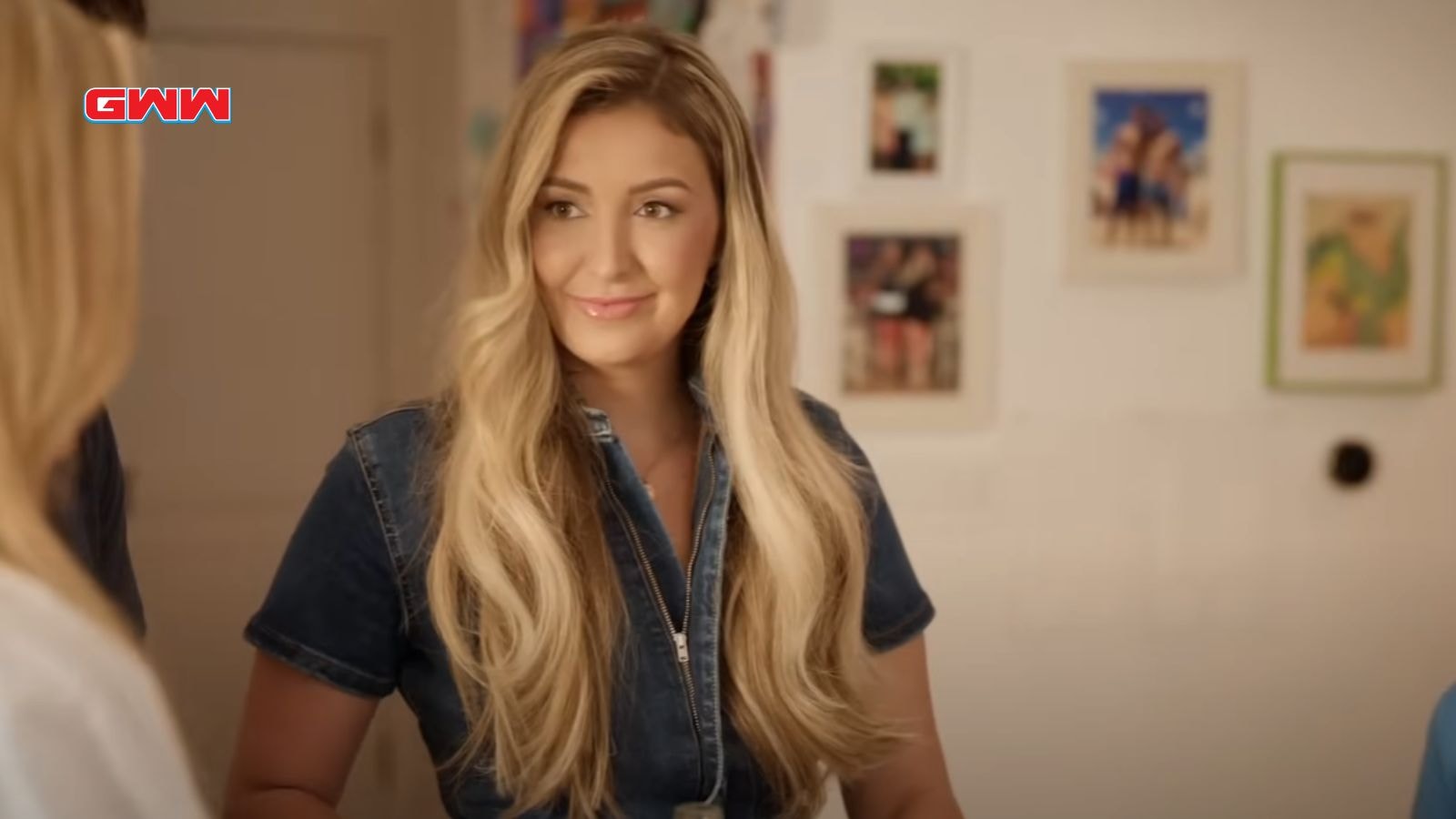 Ally with long blonde hair smiling in a casual indoor setting.