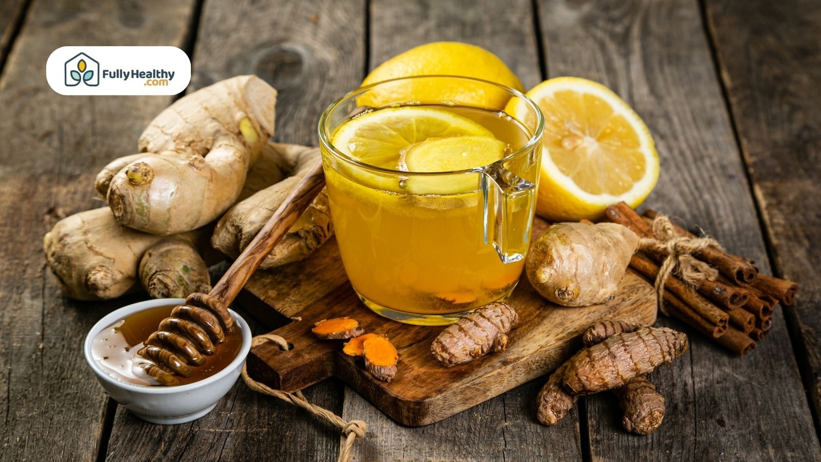 Ginger tea with lemon honey cinnamon and fresh turmeric on wood