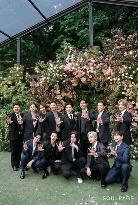 This contains an image of Super Junior
group wearing a suits and ties posing for a photo with their hands up