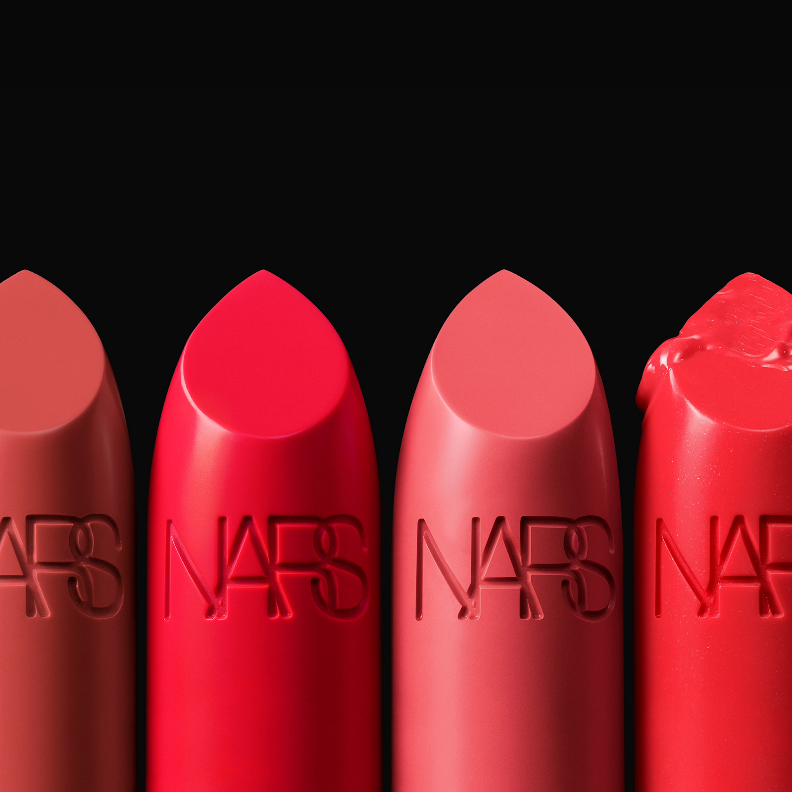 Close-up of NARS bullet lipsticks in rich reds and nudes – a top luxury lipstick brand known for intense color and creamy texture.

