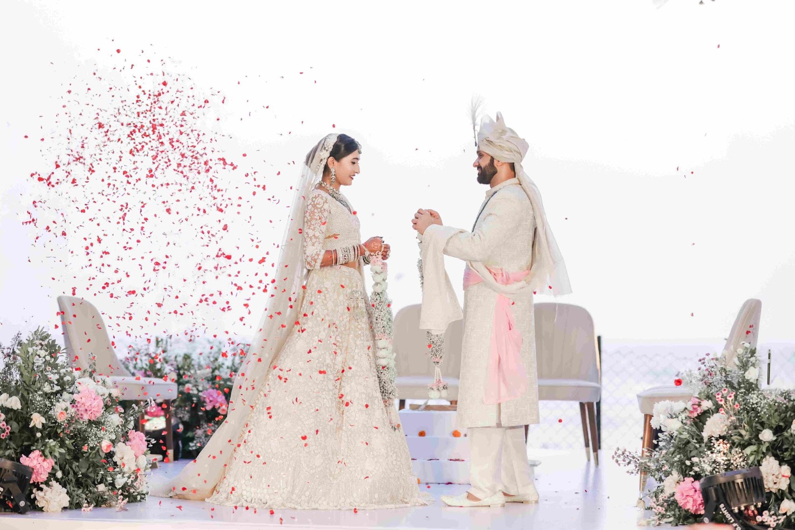 Couple standing on stage during the varmala ceremony, capturing the magical wedding moment with perfect lighting