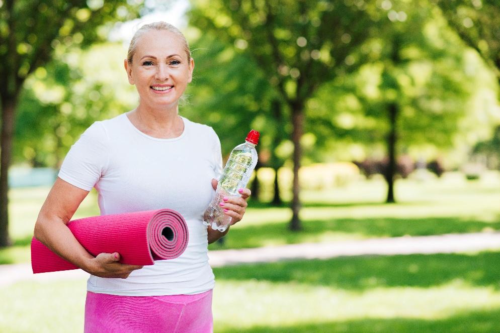 Donna che sorride e che si prepara a svolgere ginnastica in un parco.