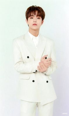 This contains an image of Park Jihoon wearing a white suit posing for the camera with his hands folded over his chest