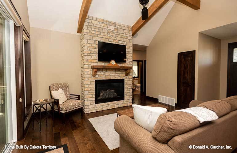 Living room with upholstered seats, tufted ottomans, and a stone fireplace with a TV on top.
