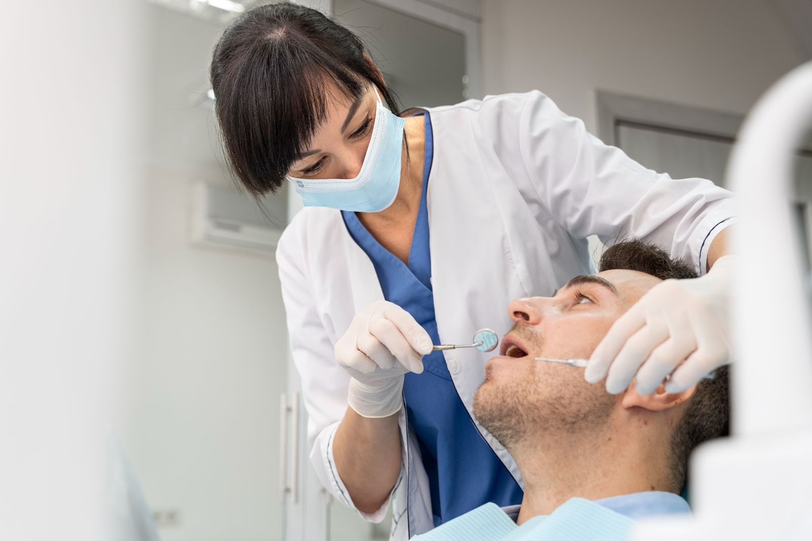 Dentist examining a male patient's teeth during a routine dental check-up at the clinic