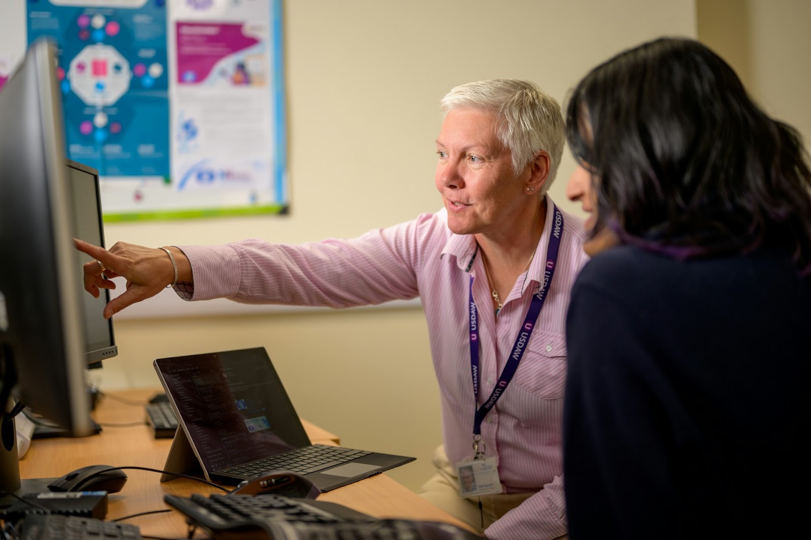 Two woman are focused on a computer screen, sharing ideas and collaborating on a project together.