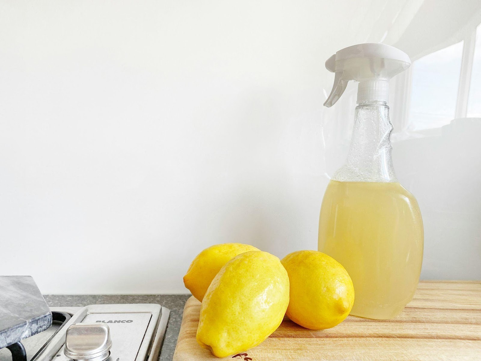 Lemons on a table alongside a spray bottle with lemon juice