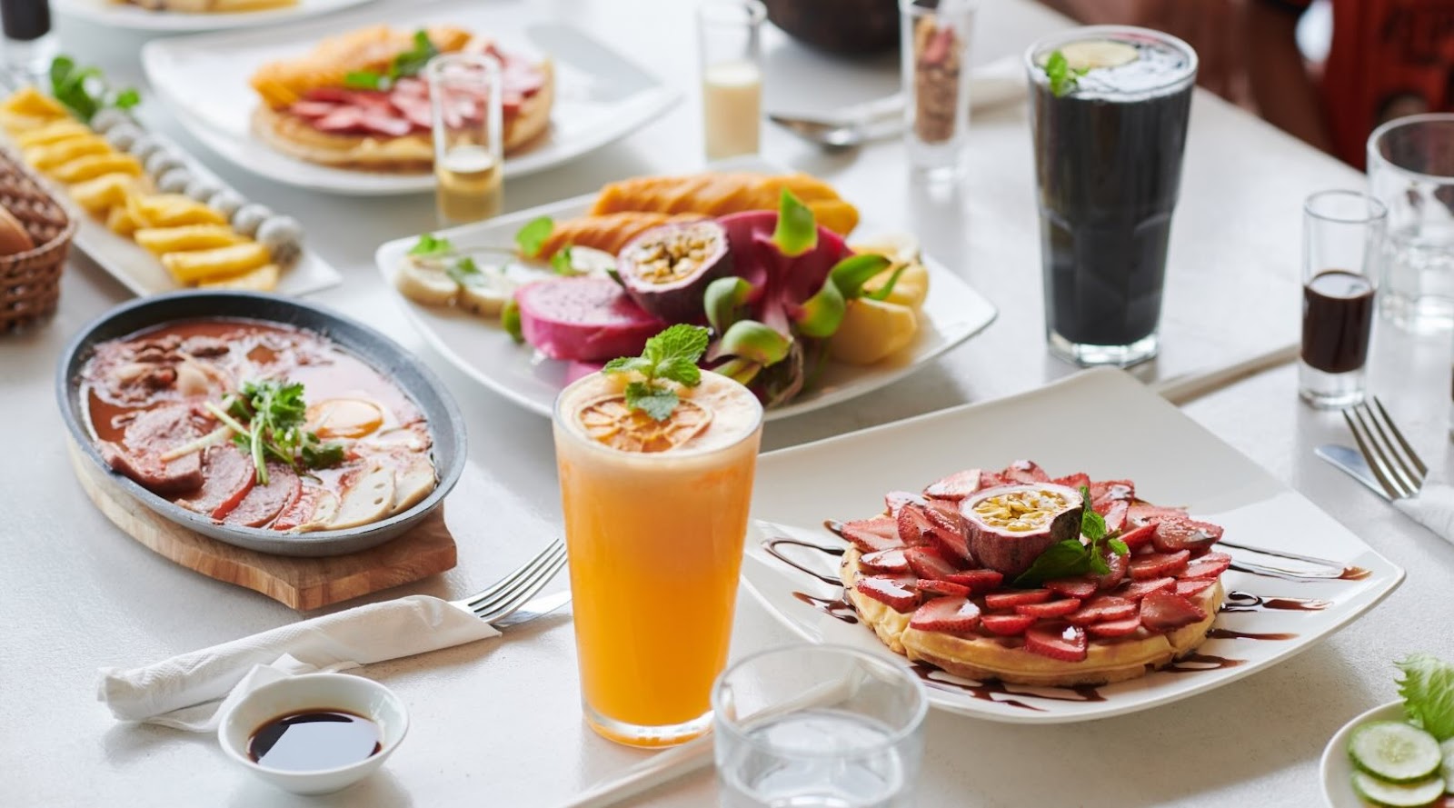 Healthy brunch spread on a beautifully set table featuring a variety of nutritious dishes including fresh fruit, waffles with strawberries, a vibrant juice, and other wholesome options. Ideal for those seeking a balanced and delicious brunch in Mississauga, recommended by our registered dietitian.