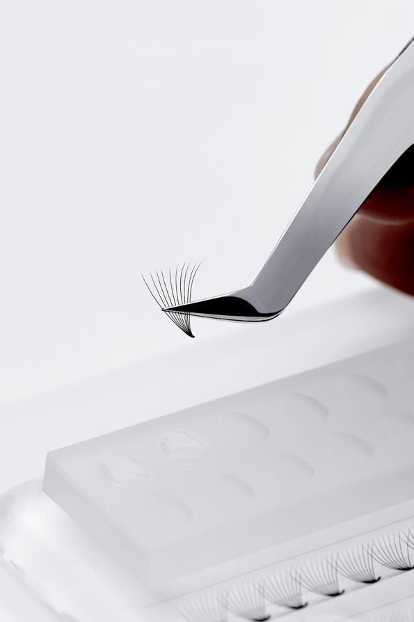 A close-up of a tweezers holding a premade volume lash fan.