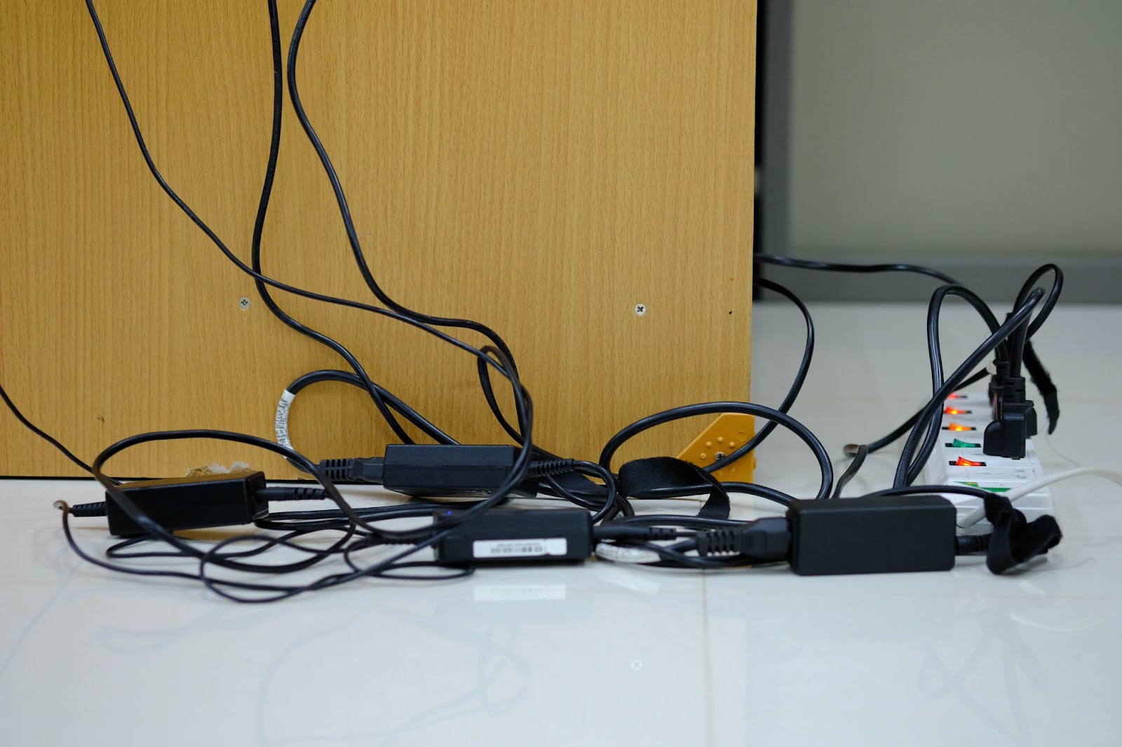 A messy tangle of electrical cords under a desk, a common physical hazard identified during an office risk assessment.