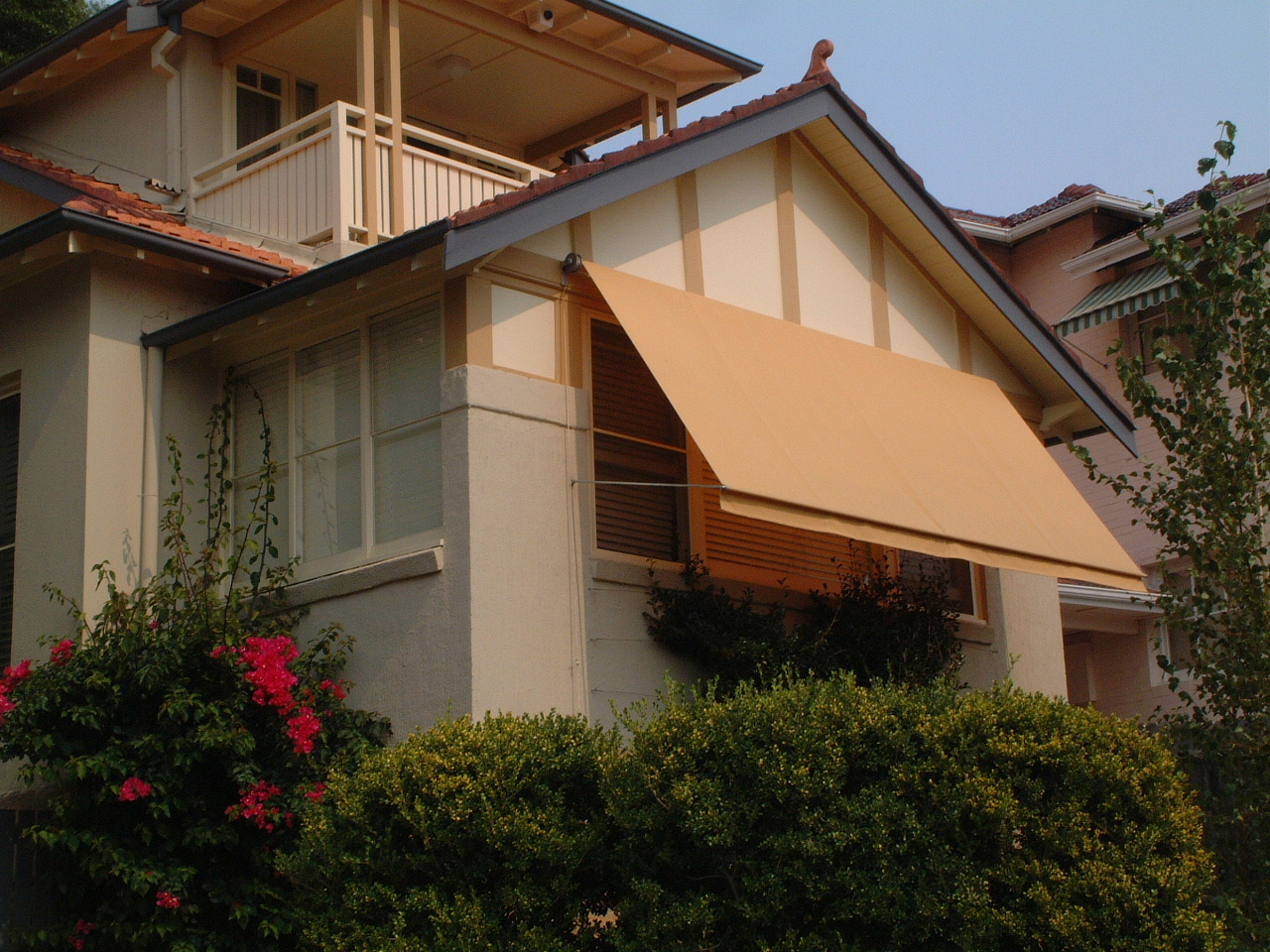 Orange pivot arm awnings providing shade to the window