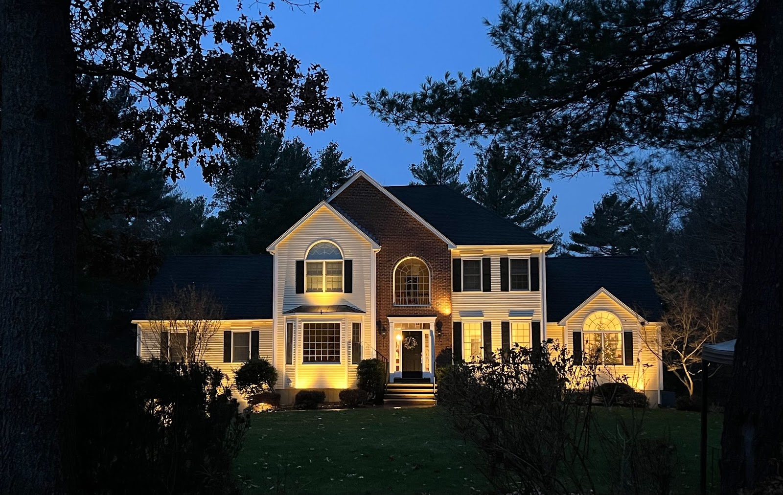 Exterior house lighting adds depth and charm to this two-story brick home