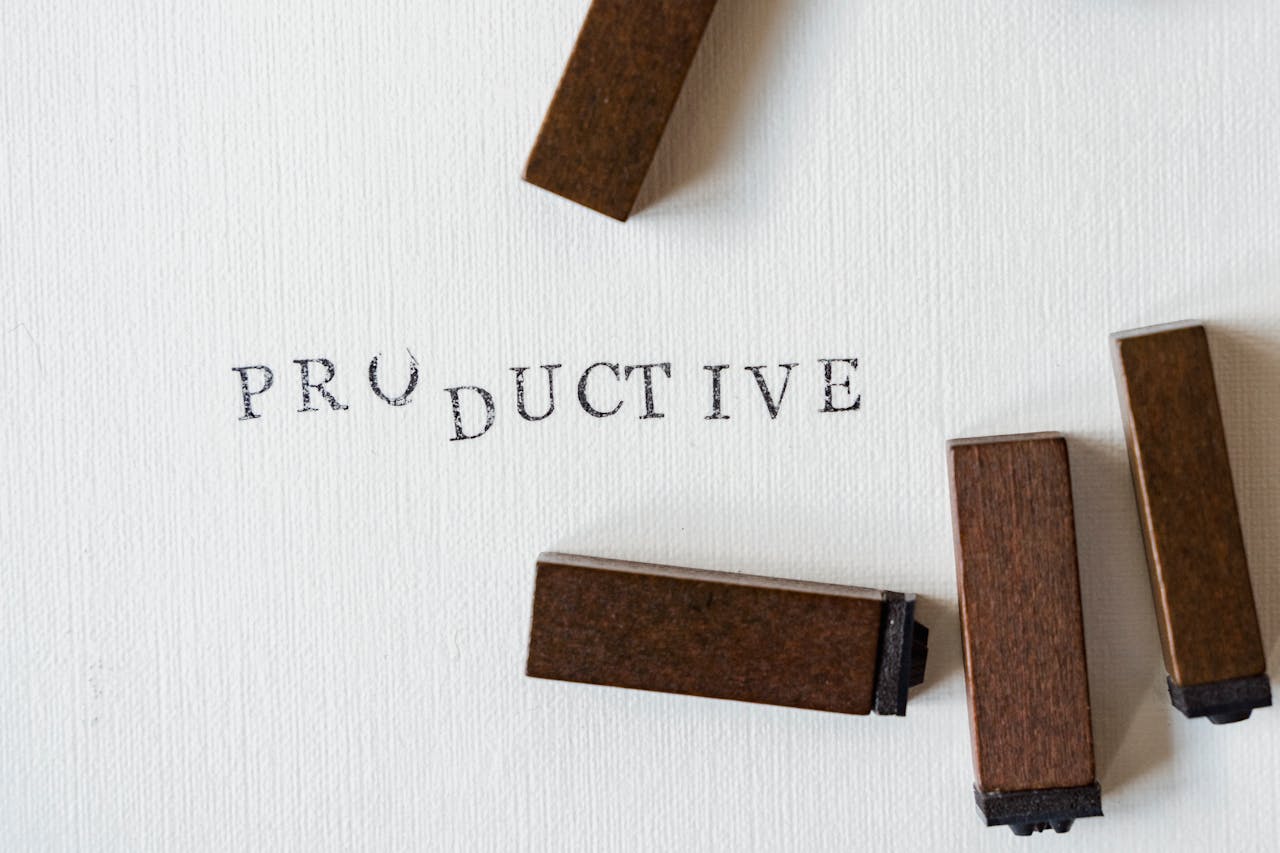 A piece of paper displays the word "productive," resting beside a wooden block, symbolizing focus and efficiency.